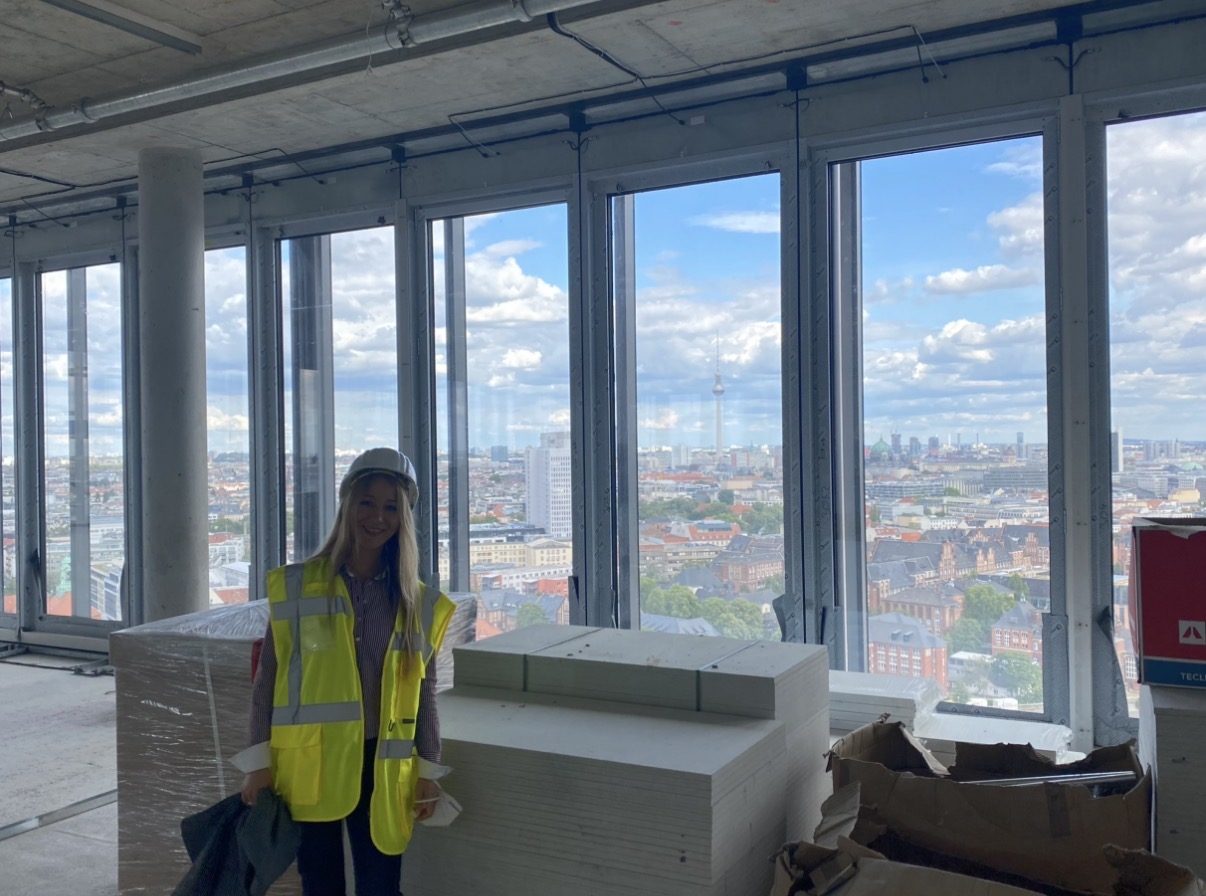 Kristina Hagewald im Rohbau eines Hochhauses mit Blick über Berlin